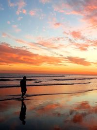 Silhouette man standing on beach against sky during sunset