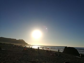 People on beach against sky during sunset