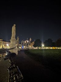 Statue in illuminated city against sky at night