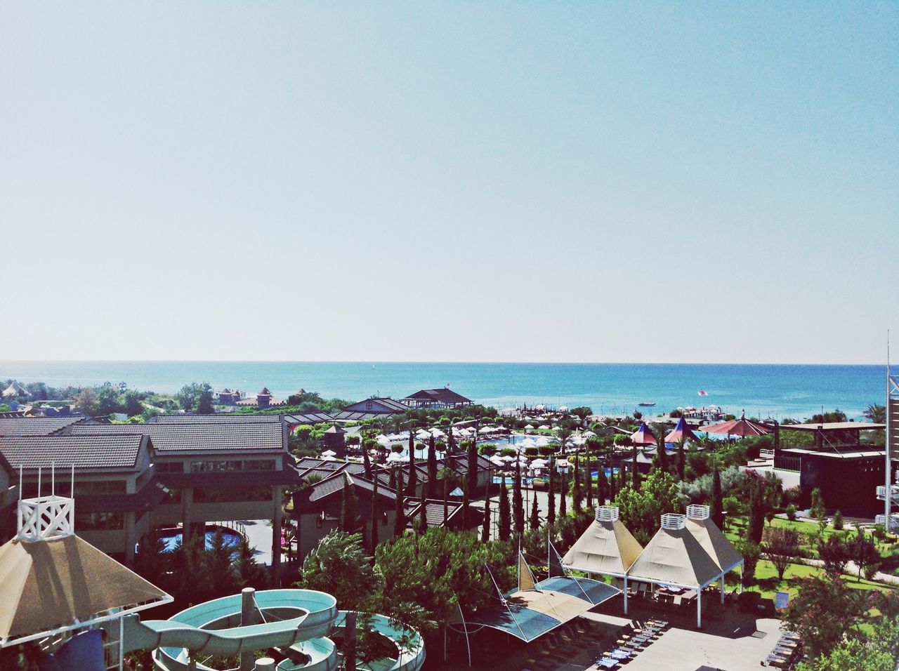 horizon over water, sea, clear sky, copy space, high angle view, built structure, architecture, building exterior, water, city, cityscape, sky, town, day, crowded, blue, outdoors, nature, tree, beach