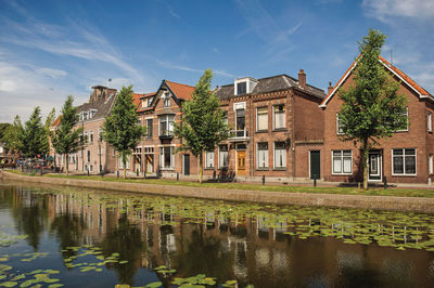 Houses by lake and buildings against sky