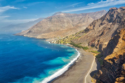 Scenic view of sea and mountains against blue sky