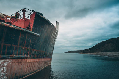 Abandoned boat on sea against sky