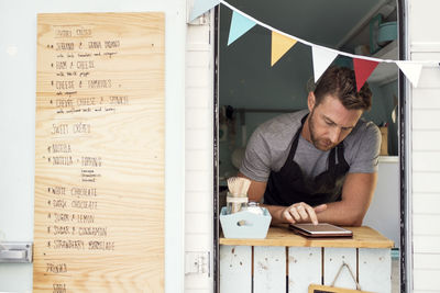 Male owner using digital tablet at food truck window