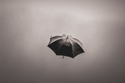 Open umbrella flying in sky . black color umbrella flying in wind.