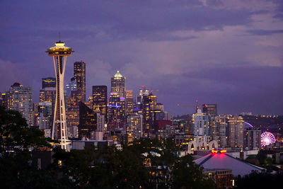 Illuminated buildings in city against sky at dusk