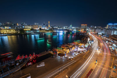 High angle view of illuminated city by buildings at night