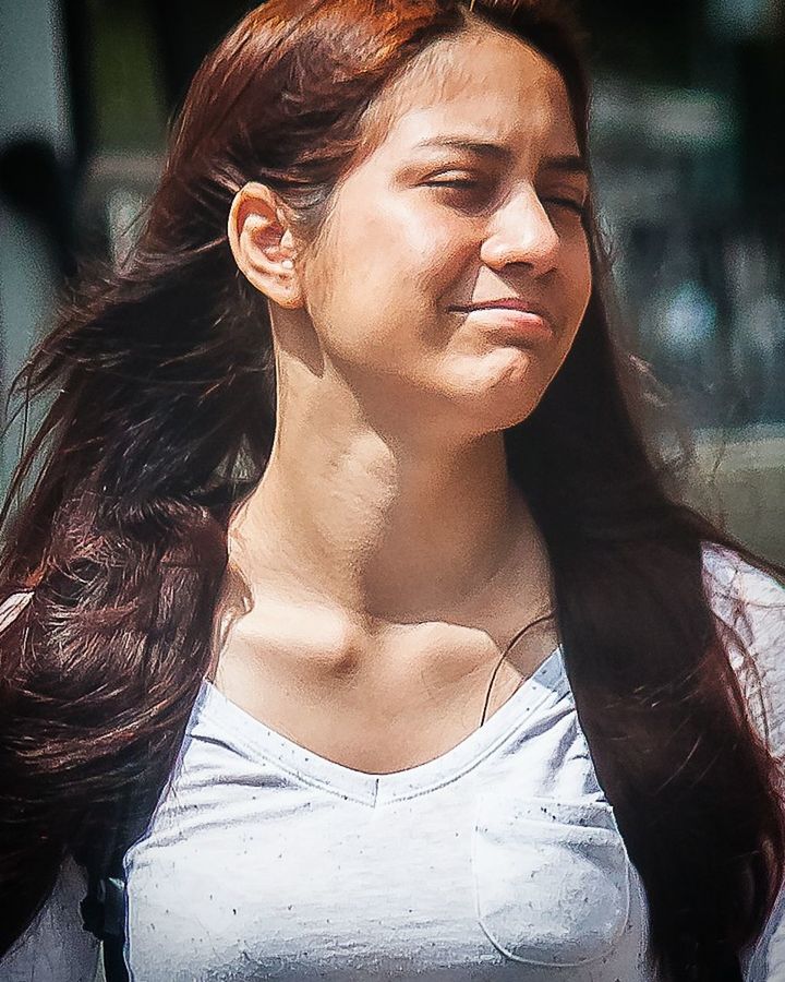 CLOSE-UP OF SMILING YOUNG WOMAN WITH HAIR IN BACKGROUND