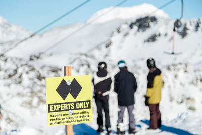 Rear view of people standing on snowcapped mountain