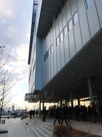 People walking on street against modern buildings in city