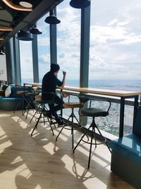 Man sitting on chair by sea against sky