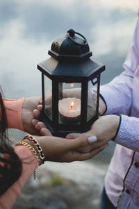 Close-up of man and woman hand holding lantern with illuminated candle