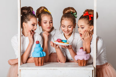 Girls having colorful macaroons against white background