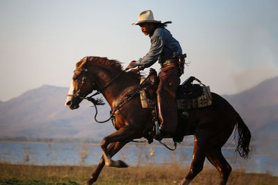 Man wearing costume riding horse against sky