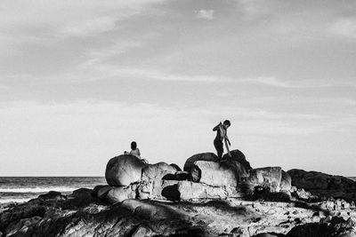 View of birds on rock by sea against sky