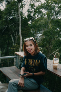 Portrait of a smiling girl sitting against trees