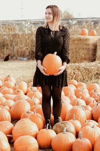 Young woman carrying pumpkins while standing on land