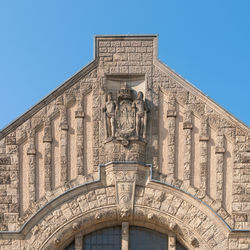 Low angle view of statue on buildings against clear blue sky