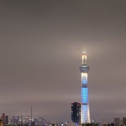 Illuminated tower in city against sky at night