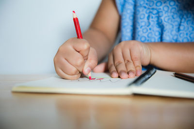 Midsection of girl drawing on book