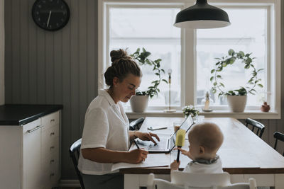 Multitasking mother taking care of baby and working from home