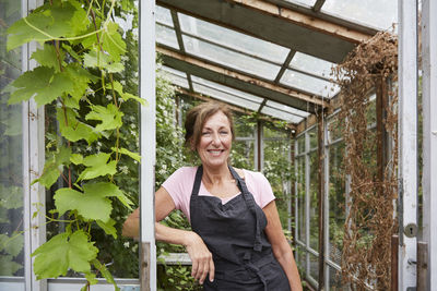 Portrait of confident gardener leaning at entrance