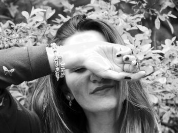 Woman covering face standing against plants