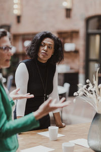 Mature businesswoman discussing with female colleague at corporate office