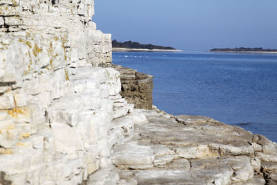 Rock formations by sea against sky