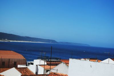 High angle view of buildings by sea against blue sky