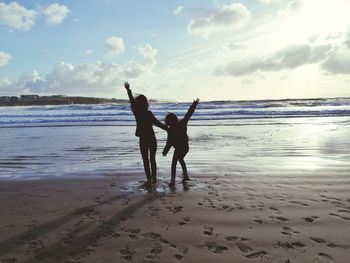 Men standing on beach against sky