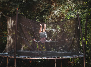 A beautiful caucasian girl in shorts and a sleeved t-shirt jumps on a trampoline