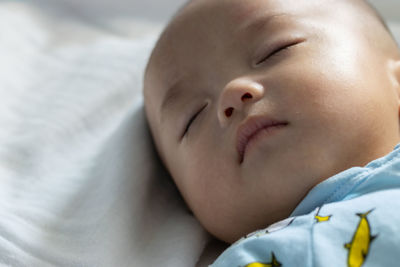 Close-up of baby sleeping on bed