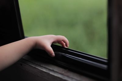 Cropped hand of child touching window
