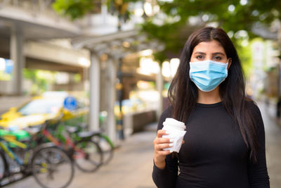 Portrait of young woman with ice cream in city