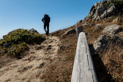 Hiker walking up hill on coastal trail in california with blue sky
