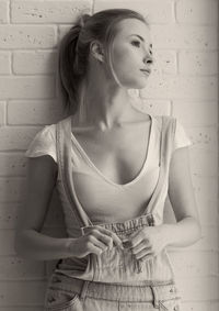 Young woman looking away while leaning on wall