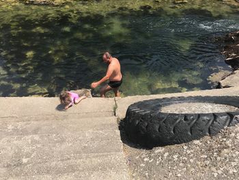 High angle view of shirtless man with daughter in river