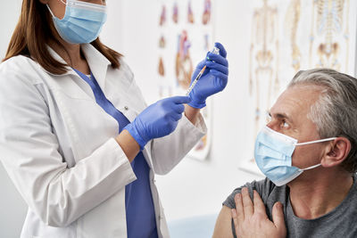 Midsection of doctor injecting syringe to patient