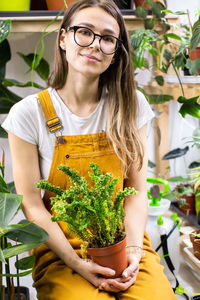 Portrait of woman holding potted plant