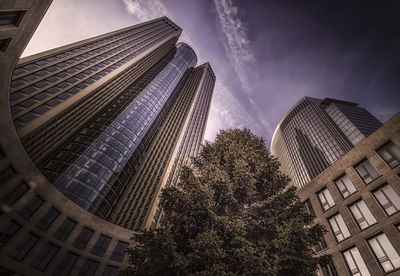 Low angle view of skyscrapers against cloudy sky