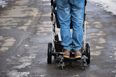 Low section of man standing over stroller on road