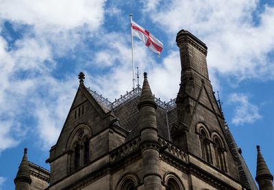 Low angle view of british flag on building against cloudy sky