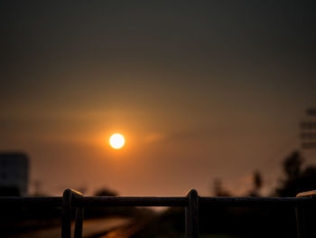 Silhouette fence against sky during sunset