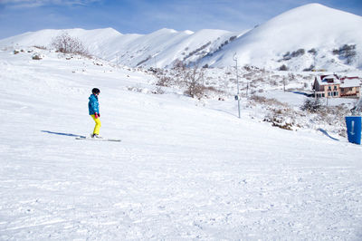 Rear view of man skiing on snow covered mountain against sky- gudauri ski resort