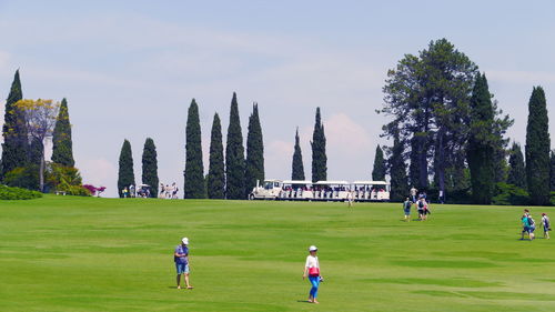 People playing soccer on field against sky