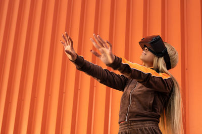 Pretty african american woman using virtual reality glasses on an orange background