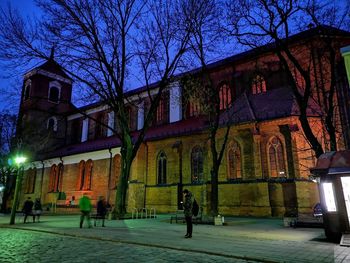 Illuminated street by building at night