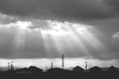 Silhouette of buildings against cloudy sky at sunset