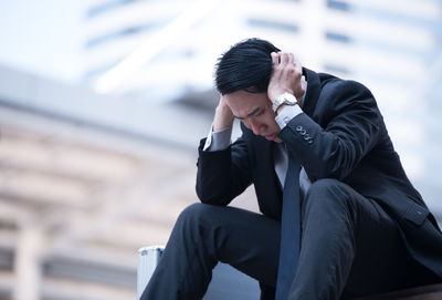 Stressed businessman sitting in city